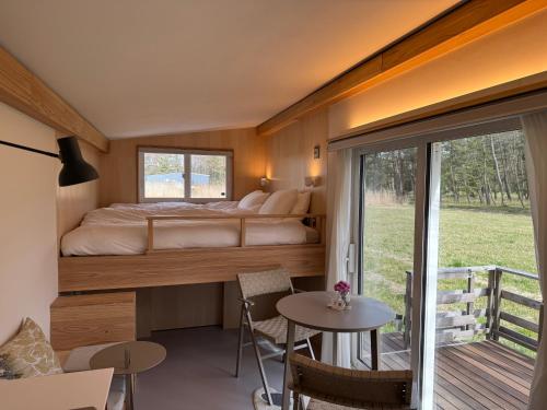 a bedroom with a bed and a table and a balcony at Cafe & Stay Flyway in Ogata