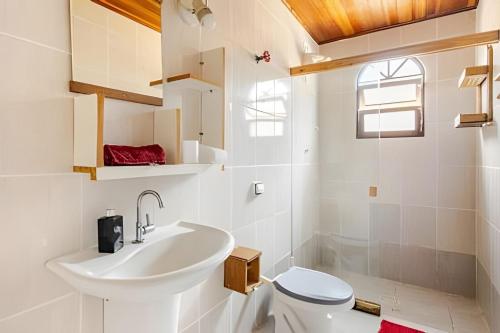 a white bathroom with a sink and a toilet at Sossego Real: Casa Solo C/ Banheira Ofuro in Ilhabela