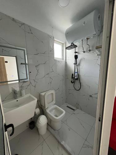 a white bathroom with a sink and a toilet at Aer Rooms Peshkopi in Peshkopi