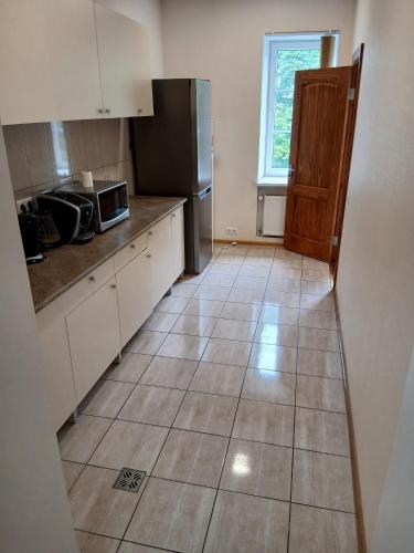 a kitchen with a refrigerator and a tile floor at Venta stay in Ventspils