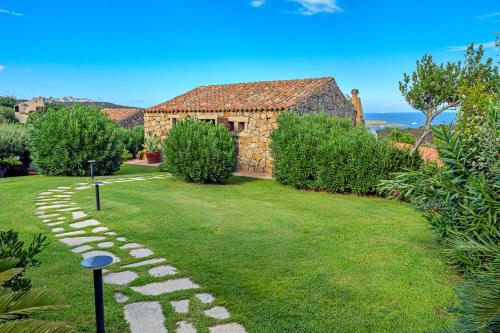 a garden with a stone path leading to a house at Domus de pedra in Marina di Portisco