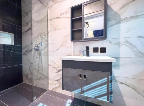 a bathroom with a sink and a mirror and a shower at Rosedale luxury apartment in Ashouman