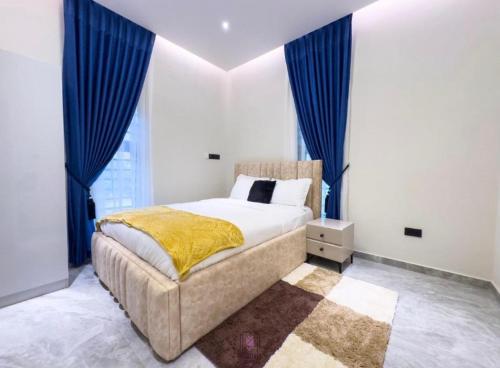 a bedroom with a large bed with blue curtains at Rosedale luxury apartment in Ashouman