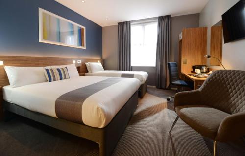 a hotel room with two beds and a chair at Travelodge Plus Galway in Galway