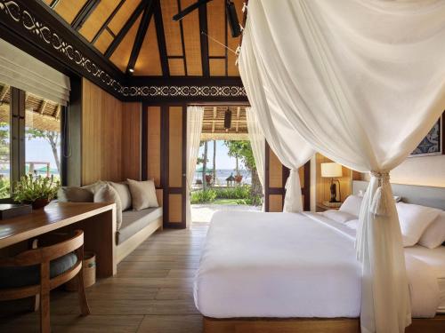 a bedroom with a bed and a desk and a table at Novotel Bali Benoa in Nusa Dua