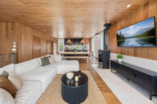 a living room with a white couch and a tv at Mountain - Sauna - Camp de base du Massif in Saint-Philémon