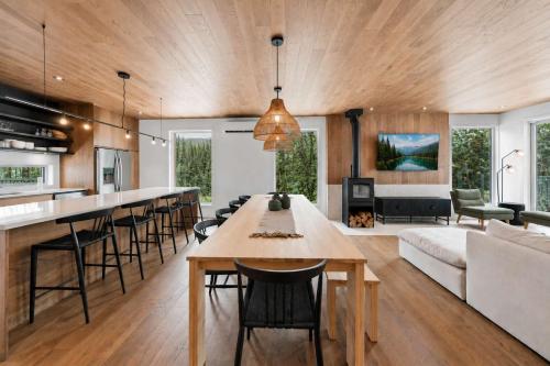a kitchen and living room with a large wooden ceiling at Mountain - Sauna - Camp de base du Massif in Saint-Philémon