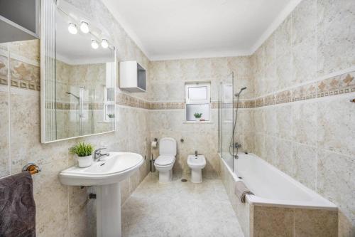 a bathroom with a sink and a toilet and a bath tub at Villa Ricardo by Villa Plus in Carvoeiro