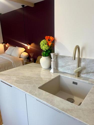 a kitchen counter with a sink and flowers on it at Nuit Céleste Studio élégant avec parking Centre Morteau in Morteau