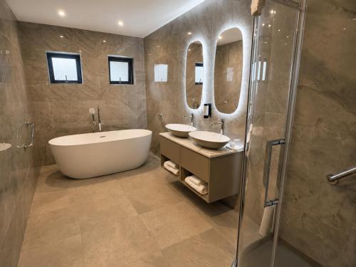 a bathroom with two sinks and a tub and mirrors at Westport Woods Hotel & Spa in Westport
