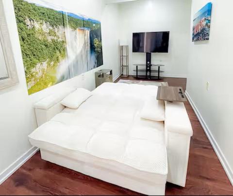 a bedroom with a white bed and a television at Central Luxury Apartments in Georgetown