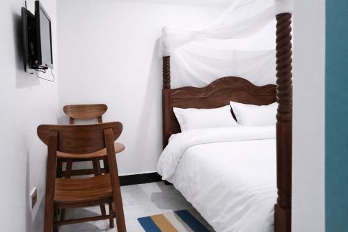 a bedroom with a bed and a chair and a television at Muzinge inn in Kagolomolo