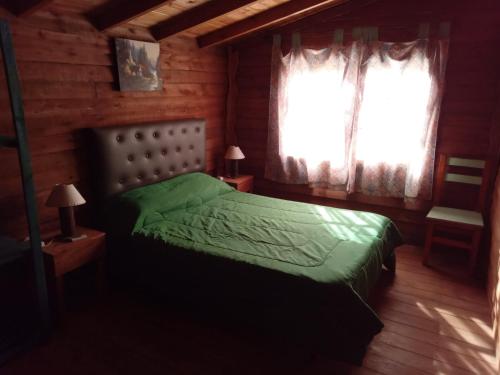 a bedroom with a green bed and a window at Complejo Medanales del Sur in Balneario Reta