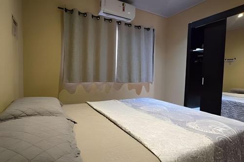 a bedroom with a bed and a window with a curtain at Chalé Ilhamar c/ garagem in Ilhabela