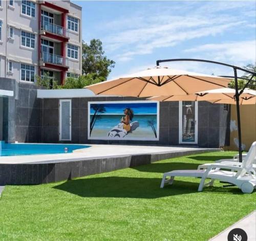 a patio with an umbrella and two chairs and a pool at Adonai Hotel & Apartment in Spintex