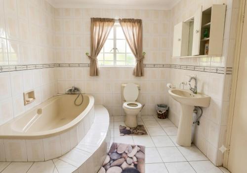 a bathroom with a tub and a toilet and a sink at Deluxe Studio Suite with Kitchenette in Gaborone