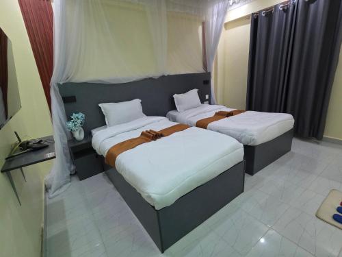 two beds in a hotel room withskirts at The alder hotel and accommodation in Bungoma