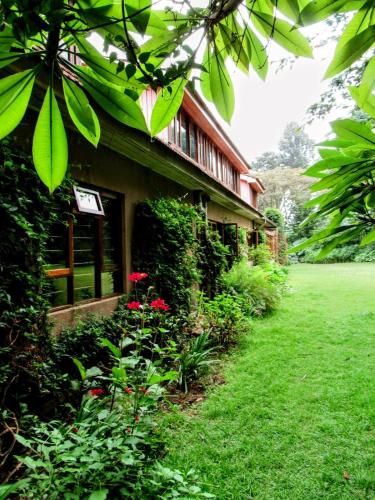 a building with green grass and flowers in front of it at The Researchers Rest in Arusha