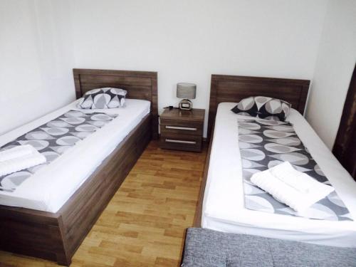two twin beds in a room with a night stand at Apartments Danex Aida in Umag