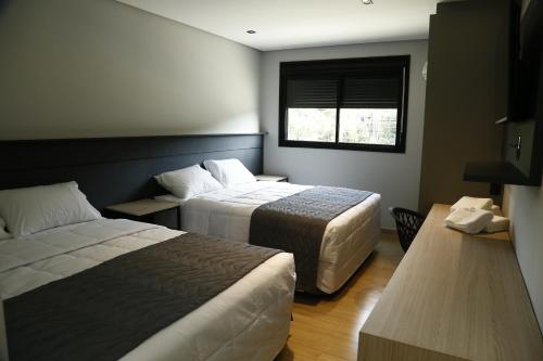 a hotel room with two beds and a window at Maranto Hotel in Pôrto União