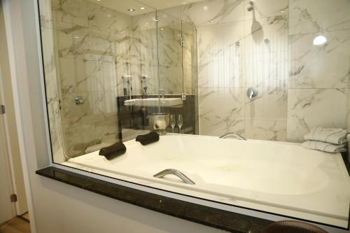 a bathroom with a bath tub with a sink at Maranto Hotel in Pôrto União