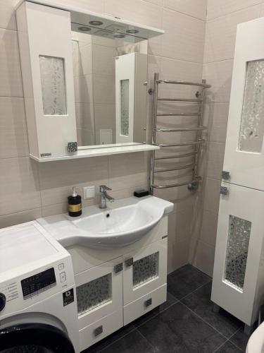 a white bathroom with a sink and a mirror at Апартаменти біля чорноморського моря in Fontanka