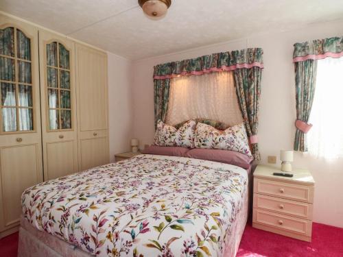 a bedroom with a bed with a floral bedspread at Buzzards Retreat in Wrexham