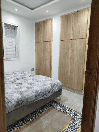 a bedroom with a bed and wooden cabinets at Appartement lemjid in Kelibia