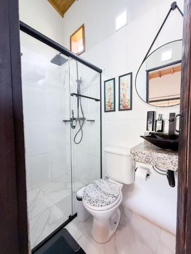 a bathroom with a toilet and a glass shower at Hospedagem Ratzke in Paraty