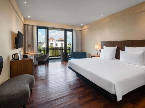 a hotel room with a large bed and a desk at Pullman Bali Legian Beach in Legian