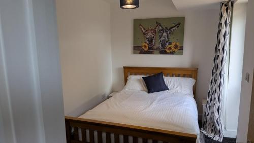 a small bedroom with a bed with white sheets and blue pillows at The Annexe in West Buckland