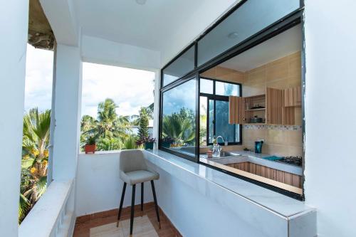 a kitchen with large windows and a counter with a stool at Dianiluxe Villa - Spacious studio 4 in Galu