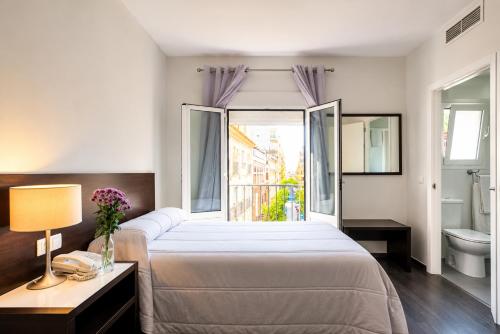 a bedroom with a bed and a bathroom with a window at Hotel Madrid de Sevilla by SHS in Seville