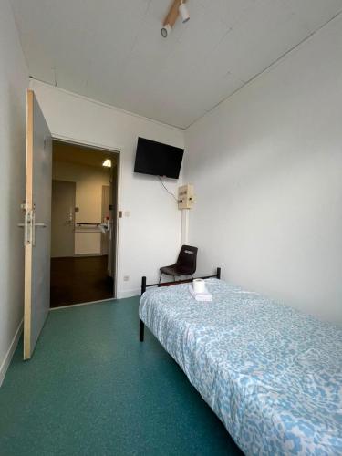 a room with a bed and a chair and a television at Le Lotus - 5 in Cherbourg en Cotentin