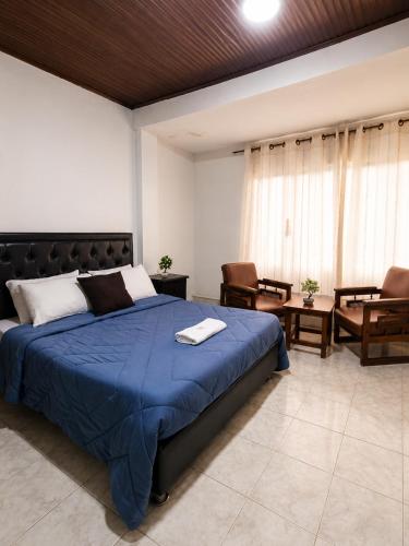 a bedroom with a bed with a blue blanket at Hotel Arauca Colonial in Arauca