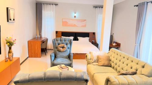 a bedroom with a bed and a couch and a chair at EZER HOMEs in Kampala