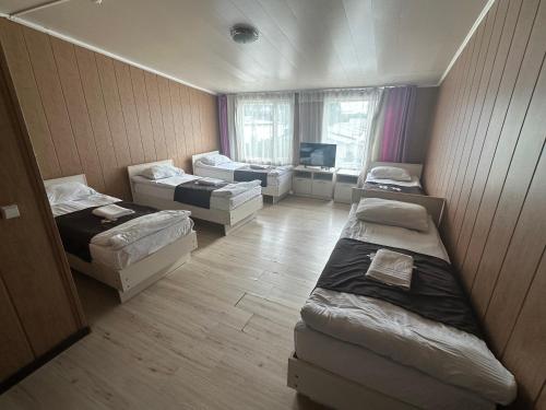 a room with three beds and a couch and a tv at Green House in Karakol