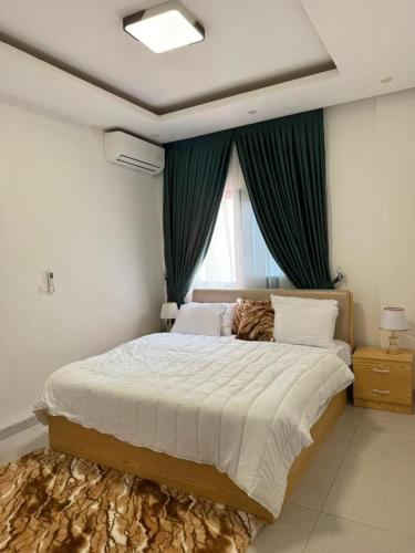 ein Schlafzimmer mit einem großen Bett und grünen Vorhängen in der Unterkunft Emeraude avec salle de sport in Dakar