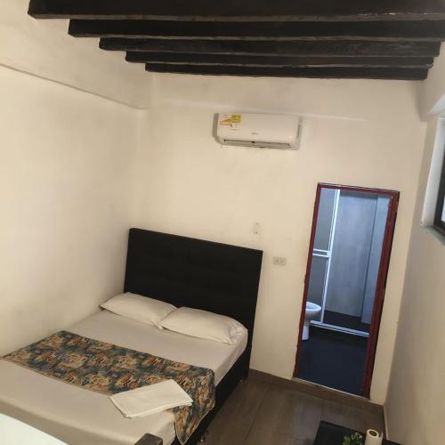 a small room with a bed and a mirror at Hostal Nomadas in Santa Marta