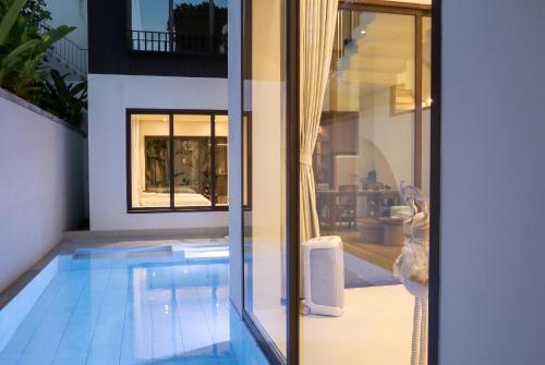 a house with a swimming pool next to a glass door at Qabalah Villa Private Pool & Rooftop Garden Stylish 2BR Retreat near Bang Tao in Ban Pak Lak