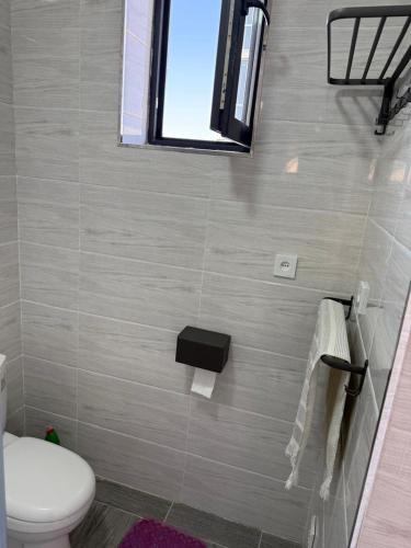 a bathroom with a toilet and a window at Alpha White Resort in Koshkolʼ