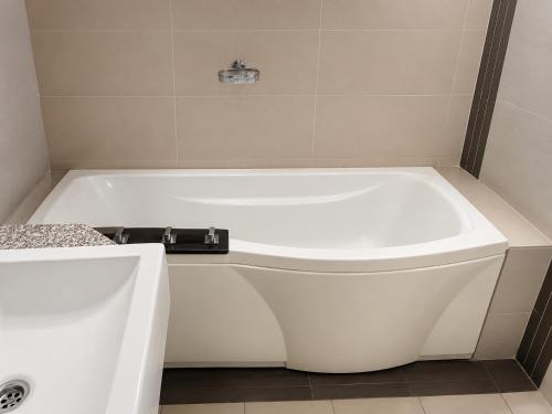 a white bath tub sitting in a bathroom at Anjung Seri Residence in Masai