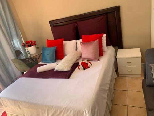 a bed with colorful pillows and flowers on it at Ecogreen on OR Tambo in Kempton Park
