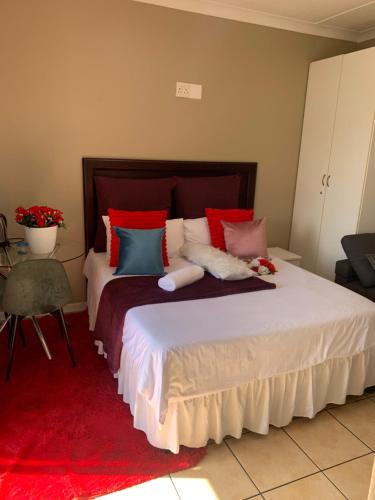a bedroom with a large bed with red and blue pillows at Ecogreen on OR Tambo in Kempton Park