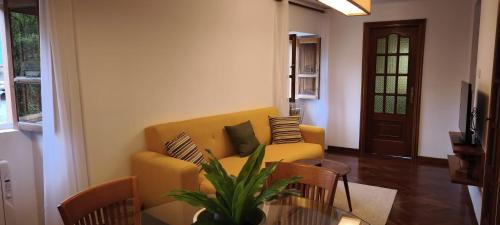 a living room with a yellow couch and a table at O retiro da Trabe in Viveiro