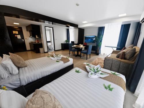 a hotel room with two beds and a couch at Dee Residence Phuket in Patong Beach