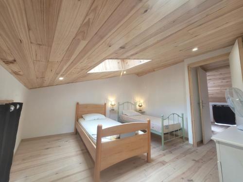 a bedroom with two beds and a wooden ceiling at Duplex des Volcans in Montaigut-le-Blanc