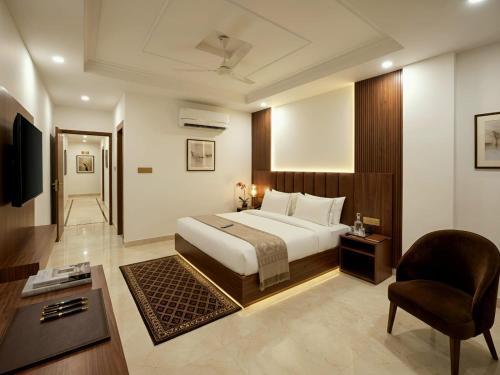 a hotel room with a bed and a chair at Palm Bliss A Luxury Hotel in Haridwār