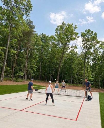a group of people playing tennis on a tennis court at Hot Tub, Secluded Hickory Tiny Home in Menlo! in Menlo