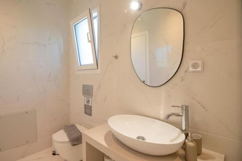 a white bathroom with a sink and a mirror at MENTOROS VILLAS in Karavádhos